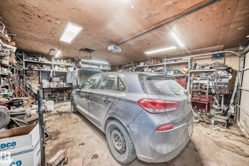 Spacious garage featuring an overhead garage door, a wooden ceiling, and ample shelving for storage - 16305 107A Ave, Edmonton, AB - Indoor Photo Showing Garage