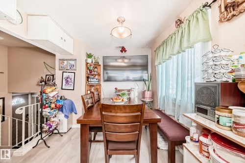 This dining area features light-colored flooring, a wooden dining table with seating, and a window with light-colored curtains - 16305 107A Ave, Edmonton, AB - Indoor