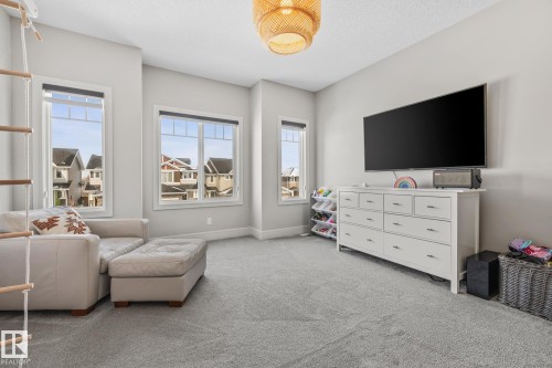 This spacious room features light grey carpeting, several large windows providing natural light, and a stylish woven light fixture - 3864 Robins Crescent, Edmonton, AB - Indoor Photo Showing Living Room
