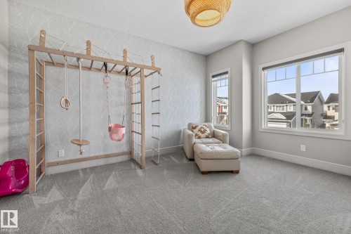 This room features grey carpeted flooring and light grey walls, with a decorative wallpaper accent wall - 3864 Robins Crescent, Edmonton, AB - Indoor