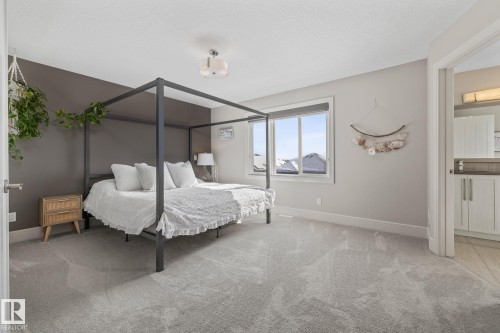 This bright room features a large window, light gray carpeting, and a contemporary ceiling light fixture - 3864 Robins Crescent, Edmonton, AB - Indoor Photo Showing Bedroom