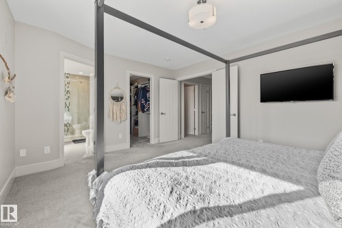 This room features soft gray carpeting, a ceiling-mounted light fixture, and an open doorway leading to a bathroom with a shower - 3864 Robins Crescent, Edmonton, AB - Indoor Photo Showing Bedroom