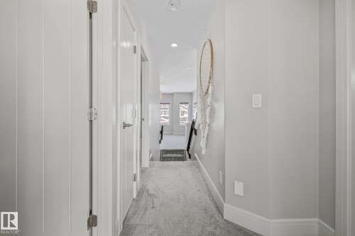 The property features a bright hallway with light grey walls, white trim, and a grey carpet - 3864 Robins Crescent, Edmonton, AB - Indoor Photo Showing Other Room
