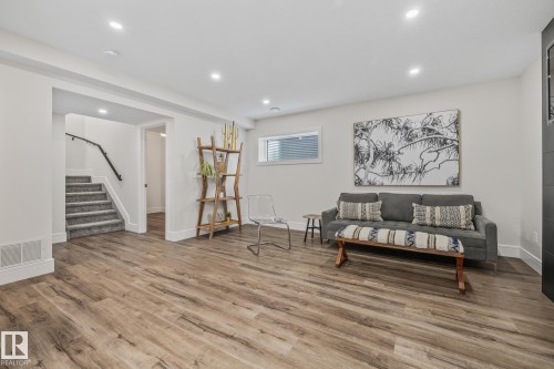 Expansive living area featuring wood-look flooring, recessed lighting, and a staircase with carpeted treads and a handrail - 3864 Robins Crescent, Edmonton, AB - Indoor