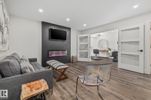 This room features wood-look flooring, a modern fireplace with a black tiled surround, and recessed lighting - 3864 Robins Crescent, Edmonton, AB - Indoor Photo Showing Living Room With Fireplace