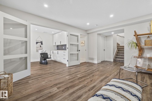 Spacious room with wood-style flooring and recessed lighting, featuring double doors opening to a separate area with a sink and cabinetry - 3864 Robins Crescent, Edmonton, AB - Indoor