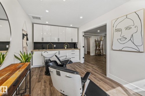 This versatile space features wood-style flooring, white upper and lower cabinetry, and a light wood countertop - 3864 Robins Crescent, Edmonton, AB - Indoor