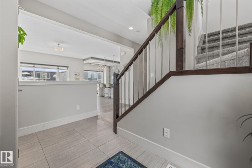 Entryway featuring light-toned tile flooring and a staircase with dark wood and metal railings - 3864 Robins Crescent, Edmonton, AB - Indoor Photo Showing Other Room