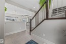 Entryway featuring light-toned tile flooring and a staircase with dark wood and metal railings - 3864 Robins Crescent, Edmonton, AB  - Indoor Photo Showing Other Room 