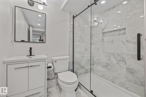 Bathroom featuring a white vanity with a rectangular sink, a black framed mirror, and a walk-in shower with a glass enclosure and marble-style tiling - 3864 Robins Crescent, Edmonton, AB - Indoor Photo Showing Bathroom