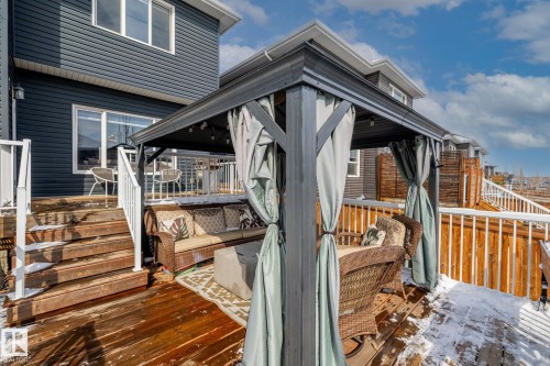 Outdoor deck featuring a dark gazebo with curtains and a seating area, alongside a white railing and wooden stairs - 3864 Robins Crescent, Edmonton, AB - Outdoor With Deck Patio Veranda With Exterior