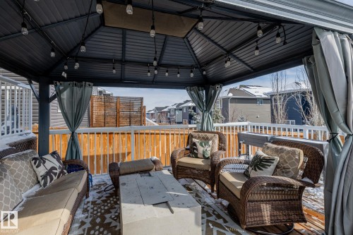The property features a covered outdoor deck area with a metal gazebo structure, string lights, and privacy curtains - 3864 Robins Crescent, Edmonton, AB - Outdoor With Deck Patio Veranda With Exterior