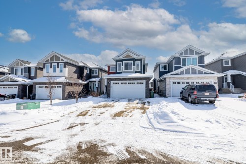 The property features a two-story architectural style with a prominent front-facing gable, a two-car garage with a white door, and a driveway - 3864 Robins Crescent, Edmonton, AB - Outdoor With Facade