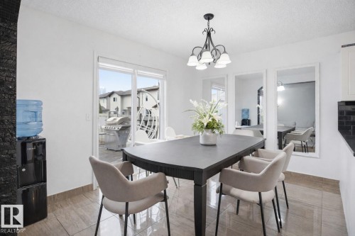 This dining area features tile flooring, a chandelier, and sliding glass doors that open to an outdoor patio - 4619 202 Street, Edmonton, AB - Indoor Photo Showing Dining Room