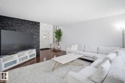 The living area features polished hardwood floors, a white door with a window, and a wall with dark stacked stone - 