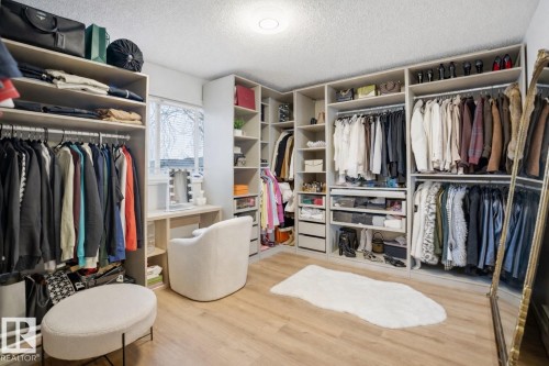 This space features extensive built-in custom closet systems with ample hanging rods and shelving - 4619 202 Street, Edmonton, AB - Indoor With Storage