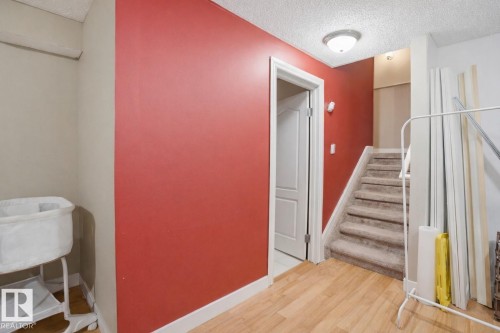 Hallway area featuring wood flooring, a doorway with white trim, and a carpeted staircase - 4619 202 Street, Edmonton, AB - Indoor Photo Showing Other Room