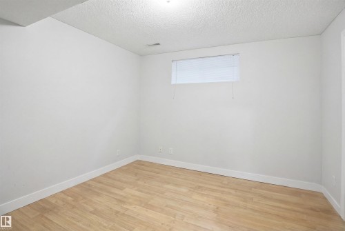 This bright room features light-toned flooring, white walls, and a window with blinds - 4619 202 Street, Edmonton, AB - Indoor Photo Showing Other Room