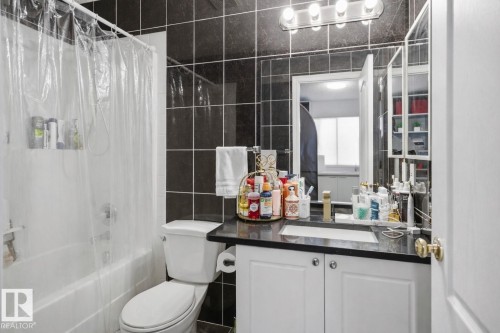 Bathroom featuring dark tiled walls, a white vanity with a dark countertop, and a shower-bathtub combination - 4619 202 Street, Edmonton, AB - Indoor Photo Showing Bathroom
