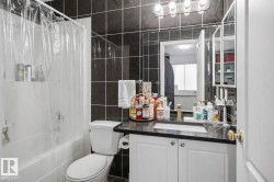 Bathroom featuring dark tiled walls, a white vanity with a dark countertop, and a shower-bathtub combination - 