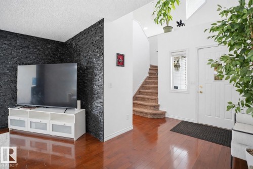 Entryway featuring hardwood flooring, a white front door with a window, and a carpeted staircase - 4619 202 Street, Edmonton, AB - Indoor Photo Showing Other Room