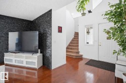 Entryway featuring hardwood flooring, a white front door with a window, and a carpeted staircase - 