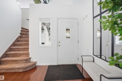 Welcoming entryway featuring hardwood flooring, a white front door with decorative glass, and a carpeted staircase - 