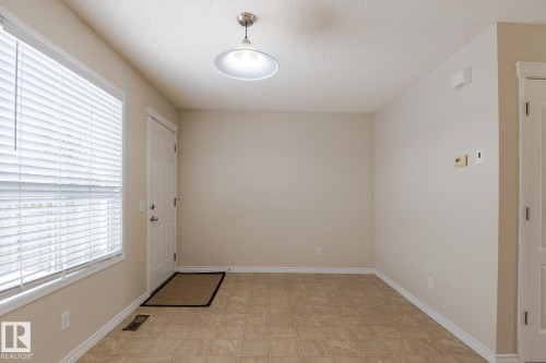 This room features tiled flooring, a window with blinds, and a ceiling-mounted light fixture - 58 Birchmont Drive, Leduc, AB - Indoor Photo Showing Other Room