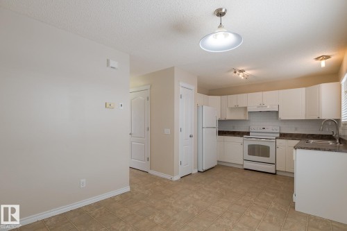 The kitchen features white cabinetry, white appliances, and granite-style countertops - 58 Birchmont Drive, Leduc, AB - Indoor Photo Showing Kitchen