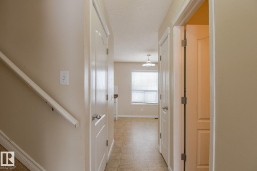 Hallway featuring neutral-toned walls, tile flooring, and a window with blinds providing natural light - 58 Birchmont Drive, Leduc, AB - Indoor Photo Showing Other Room