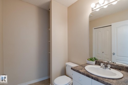 Bathroom featuring a vanity with an integrated sink, a toilet, and a mirror with overhead lighting - 58 Birchmont Drive, Leduc, AB - Indoor Photo Showing Bathroom