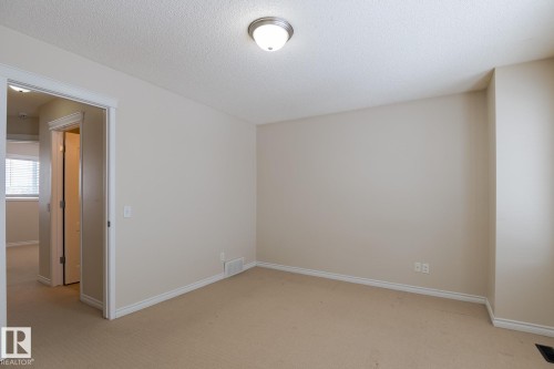 This inviting room features neutral-toned carpet, light-colored walls, and a ceiling light fixture - 58 Birchmont Drive, Leduc, AB - Indoor Photo Showing Other Room