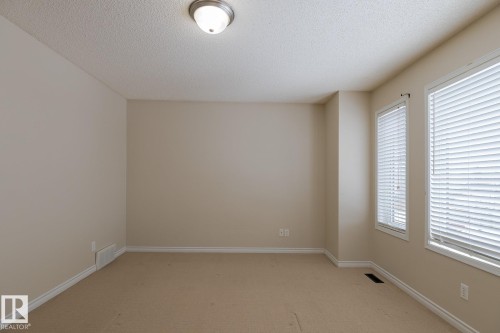 This space features neutral-toned walls, carpeted flooring, and two windows with blinds, providing natural light - 58 Birchmont Drive, Leduc, AB - Indoor Photo Showing Other Room