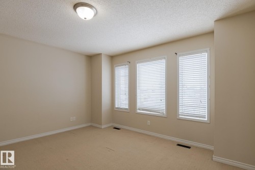 Bright room featuring a neutral color palette, three windows with blinds, and carpeted flooring - 58 Birchmont Drive, Leduc, AB - Indoor Photo Showing Other Room