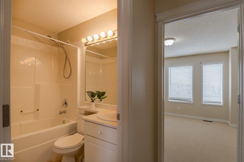 The property features a bathroom with a shower and bathtub combination, a toilet, a vanity with a sink, and a mirror with overhead lighting - 58 Birchmont Drive, Leduc, AB - Indoor Photo Showing Bathroom