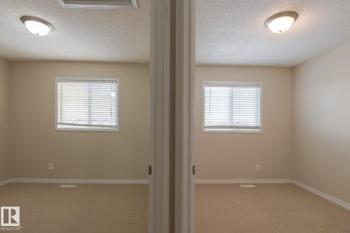 This room features neutral-toned walls, carpeted flooring, a window with blinds, and a ceiling-mounted light fixture - 58 Birchmont Drive, Leduc, AB - Indoor Photo Showing Other Room