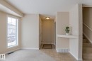The property features a bright living area with a large window, a main entrance with tiled flooring, and a carpeted staircase - 58 Birchmont Drive, Leduc, AB  - Indoor Photo Showing Other Room 