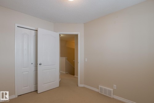 The room features neutral-toned walls, a textured ceiling, and carpeting - 58 Birchmont Drive, Leduc, AB - Indoor