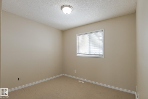 This room features neutral-toned walls, a window with blinds, and carpeted flooring - 58 Birchmont Drive, Leduc, AB - Indoor Photo Showing Other Room