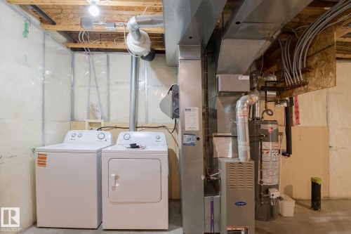 The property features a dedicated laundry area with a washer and dryer, alongside a furnace and water heater - 58 Birchmont Drive, Leduc, AB - Indoor Photo Showing Laundry Room