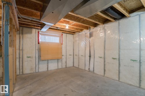 Unfinished space featuring exposed wooden ceiling joists, insulation, and a window - 58 Birchmont Drive, Leduc, AB - Indoor Photo Showing Basement