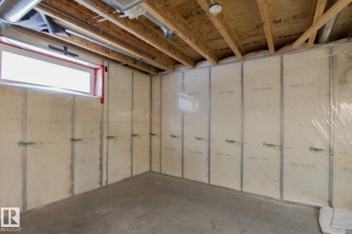 The unfinished basement features exposed wood ceiling joists, a concrete floor, and insulation panels along the walls - 58 Birchmont Drive, Leduc, AB - Indoor Photo Showing Basement