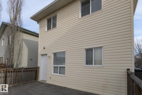 The property features a two-story exterior with light-colored siding, multiple windows, and a white exterior door - 58 Birchmont Drive, Leduc, AB - Outdoor With Exterior