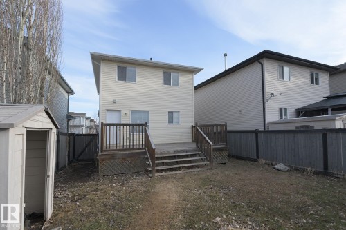 The property features a wood deck with stairs, a backyard with a lawn, and a small shed - 58 Birchmont Drive, Leduc, AB - Outdoor With Exterior