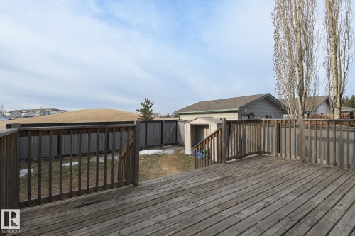 The property features a wooden deck with railing, offering views of the fenced yard and a detached shed - 58 Birchmont Drive, Leduc, AB - Outdoor With Deck Patio Veranda With Exterior