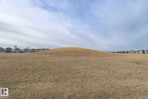 Expansive open field with a gently sloping hill and distant residential properties - 58 Birchmont Drive, Leduc, AB - Outdoor With View