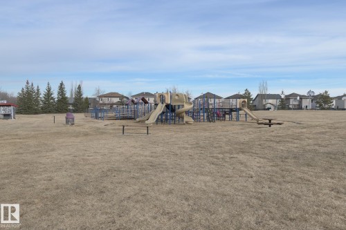 Community playground featuring slides, climbing structures, and a picnic table - 58 Birchmont Drive, Leduc, AB - Outdoor