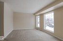This bright room features neutral-toned walls, plush carpeting, and large windows that provide abundant natural light - 58 Birchmont Drive, Leduc, AB  - Indoor Photo Showing Other Room 