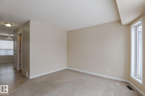 This room features neutral-toned carpet, light-colored walls, and a window providing natural light - 58 Birchmont Drive, Leduc, AB - Indoor Photo Showing Other Room