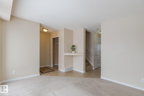 Bright entry area with neutral-toned walls, carpeted flooring, and a tiled entryway - 58 Birchmont Drive, Leduc, AB - Indoor Photo Showing Other Room
